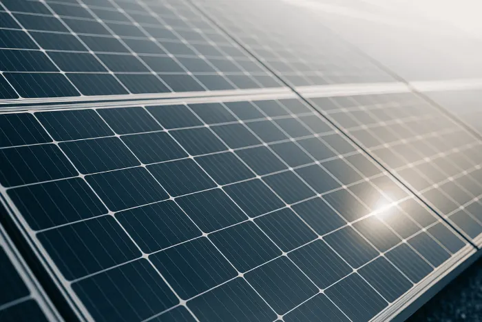 Nahaufnahme von modernen Solarmodulen einer Photovoltaikanlage mit reflektierendem Sonnenlicht.